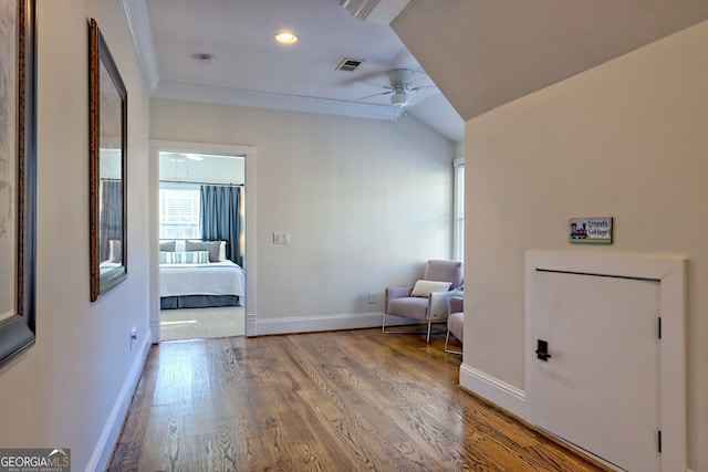 hall with lofted ceiling, wood-type flooring, and ornamental molding