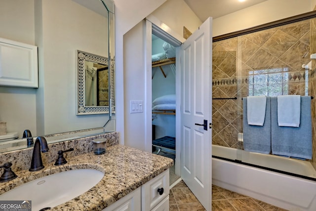 bathroom with tile patterned flooring, bath / shower combo with glass door, and vanity