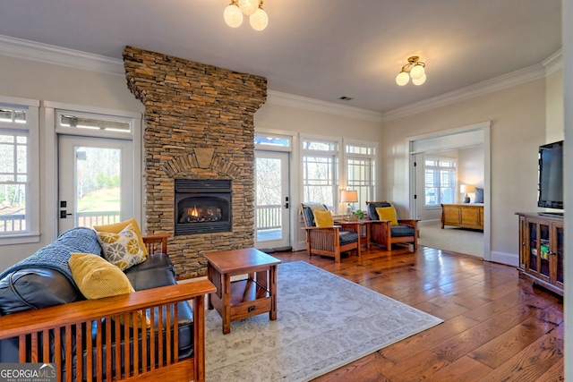 living room featuring ornamental molding, a healthy amount of sunlight, hardwood / wood-style floors, and a fireplace