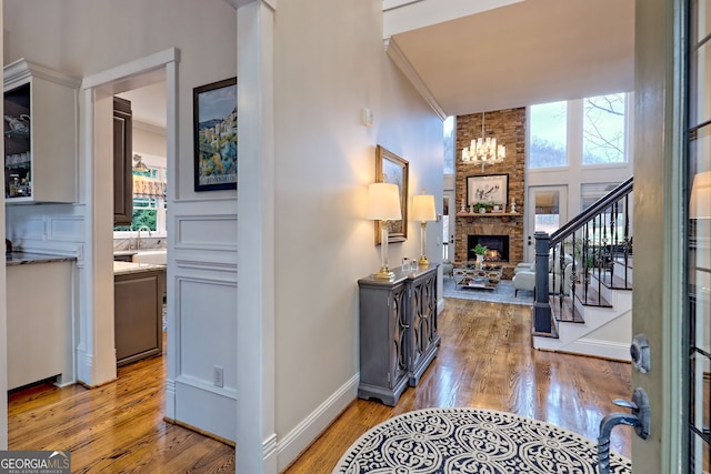 entryway with ornamental molding, light hardwood / wood-style flooring, a wealth of natural light, and a stone fireplace