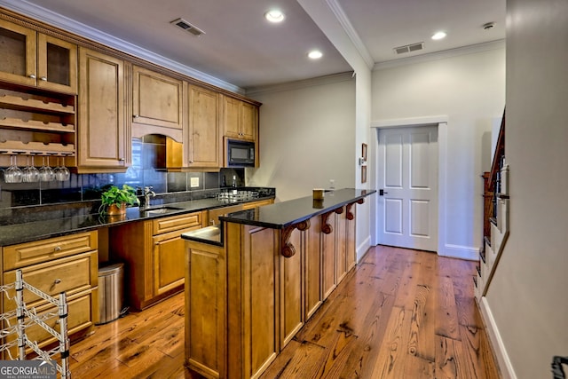 kitchen with sink, dark stone counters, black microwave, and crown molding