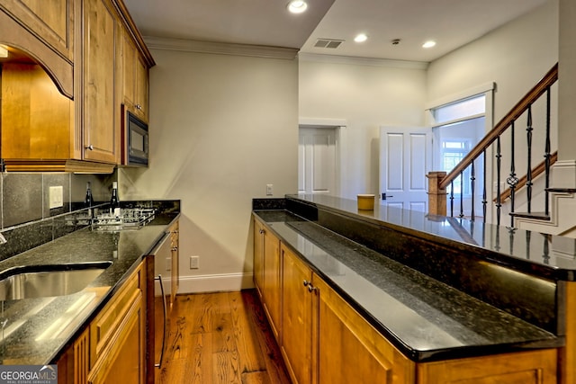 kitchen featuring hardwood / wood-style floors, dishwasher, black microwave, dark stone counters, and ornamental molding