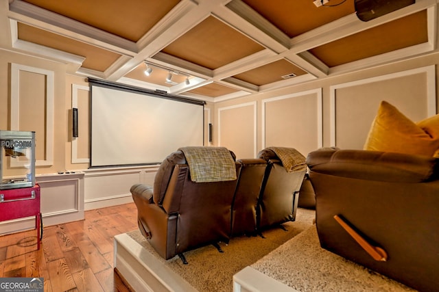 cinema with coffered ceiling, light wood-type flooring, crown molding, and beam ceiling