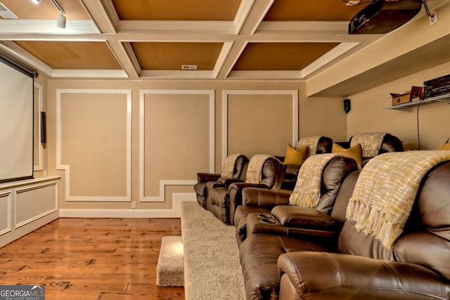 home theater room with coffered ceiling, beamed ceiling, light wood-type flooring, and crown molding