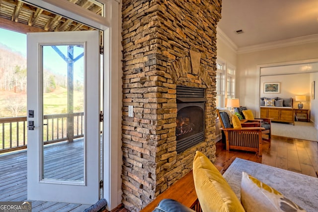 living room with a fireplace, crown molding, a wealth of natural light, and hardwood / wood-style floors