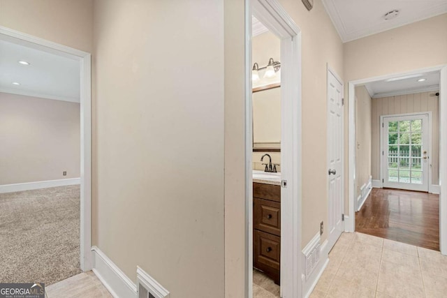 hall with sink, ornamental molding, and light tile patterned floors