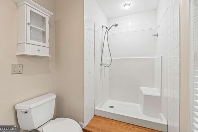 bathroom with a tile shower and toilet