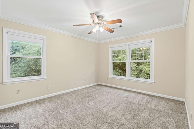 carpeted empty room with ceiling fan, ornamental molding, and a wealth of natural light