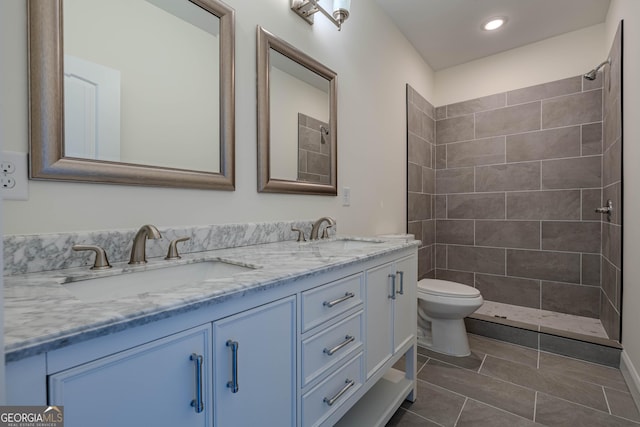 bathroom with a tile shower, vanity, and toilet