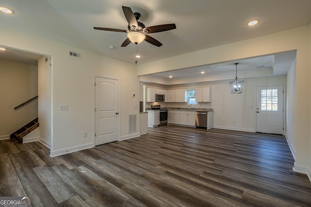 unfurnished living room featuring a tray ceiling, dark hardwood / wood-style flooring, ceiling fan with notable chandelier, and sink