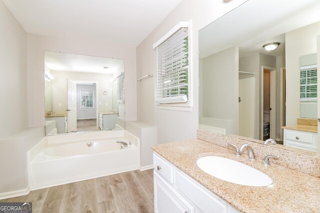 bathroom featuring a washtub, hardwood / wood-style floors, toilet, and a healthy amount of sunlight