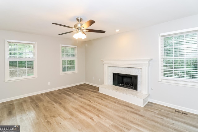 unfurnished living room featuring a wealth of natural light, ceiling fan, and light hardwood / wood-style floors