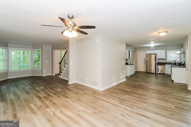 unfurnished living room with ceiling fan, light hardwood / wood-style floors, and sink