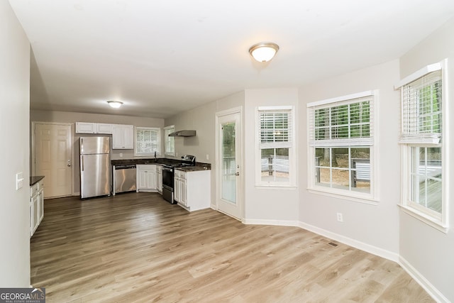 kitchen with ventilation hood, white cabinets, stainless steel appliances, and light hardwood / wood-style floors