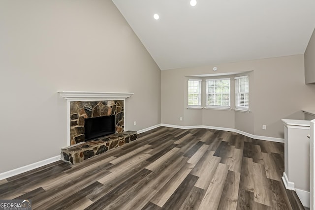 unfurnished living room featuring a stone fireplace, dark hardwood / wood-style flooring, and vaulted ceiling