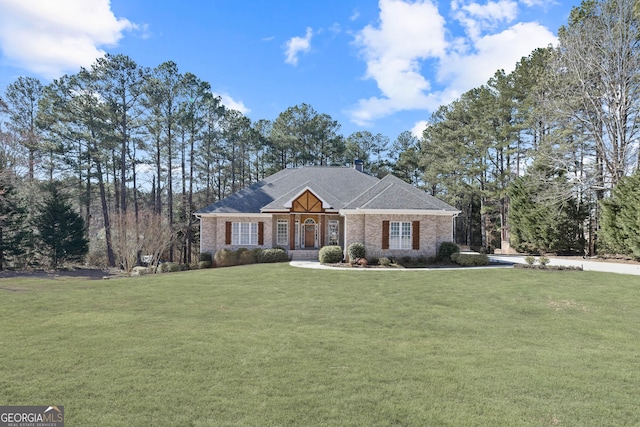 view of front of home featuring a shingled roof, a front yard, brick siding, and a chimney