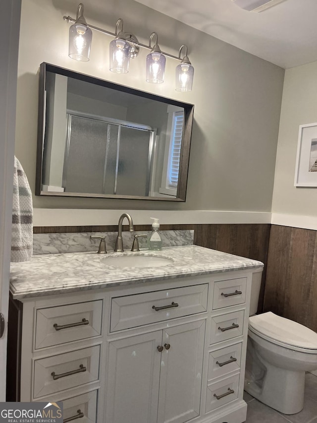 bathroom featuring vanity, walk in shower, toilet, and wood walls