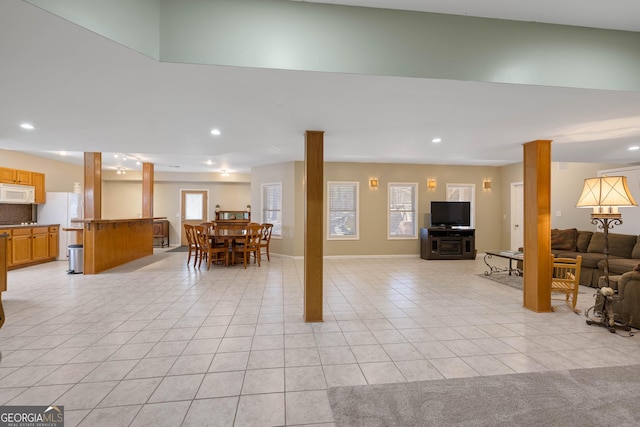 kitchen featuring light stone countertops, white appliances, decorative columns, and light tile patterned floors