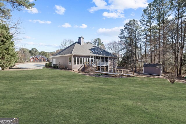 rear view of house with a sunroom, a chimney, and a deck