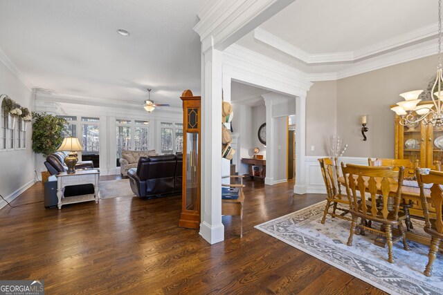 living room with dark wood-style floors, a lit fireplace, ornamental molding, and ceiling fan