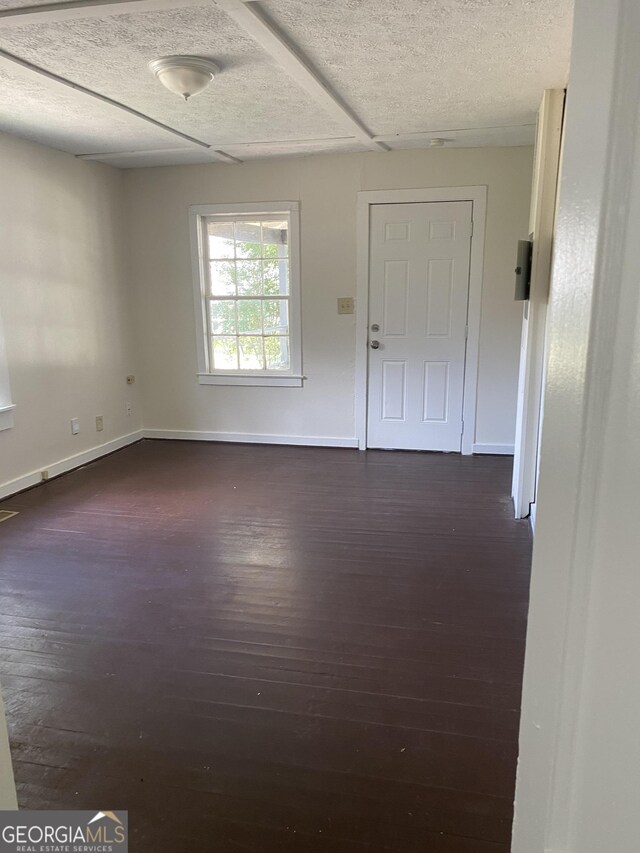 empty room featuring a textured ceiling and dark hardwood / wood-style floors