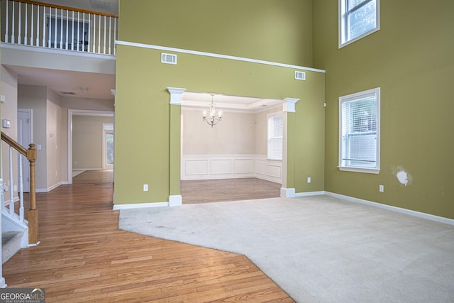 interior space featuring a notable chandelier, a healthy amount of sunlight, light colored carpet, and crown molding