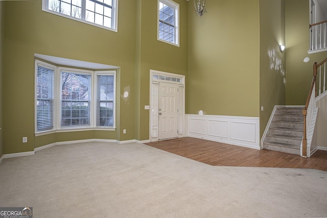 entryway featuring a towering ceiling, hardwood / wood-style flooring, and an inviting chandelier