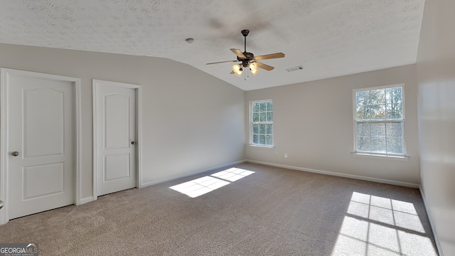 unfurnished bedroom featuring ceiling fan, light colored carpet, a textured ceiling, and vaulted ceiling