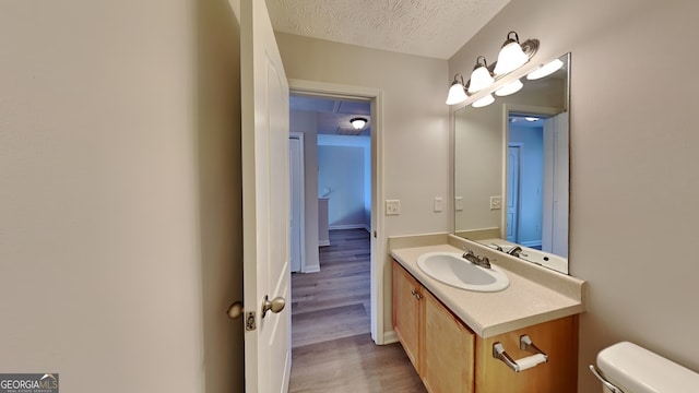 bathroom featuring vanity, toilet, wood-type flooring, and a textured ceiling