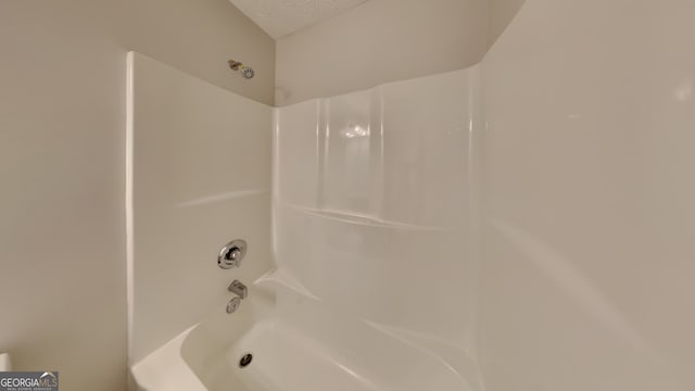 bathroom featuring a textured ceiling and tub / shower combination