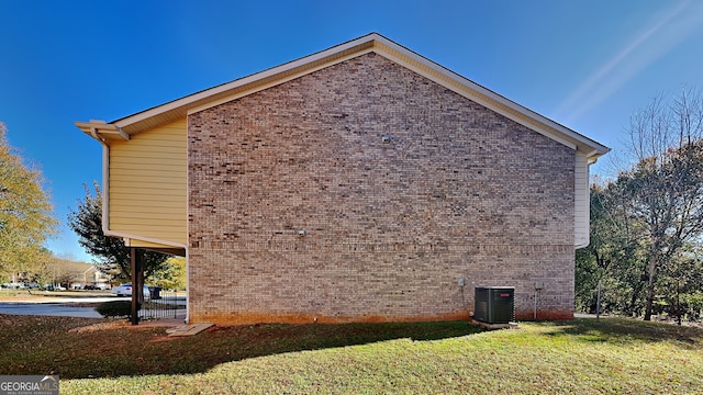 view of side of property with central air condition unit and a yard