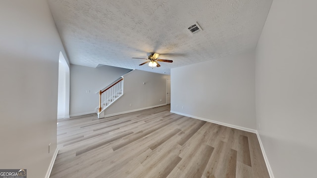 unfurnished living room with ceiling fan, light wood-type flooring, and a textured ceiling