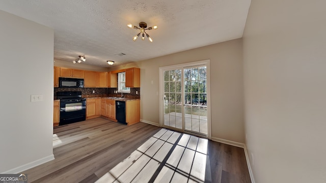 kitchen featuring a textured ceiling, sink, light hardwood / wood-style floors, and black appliances