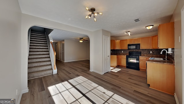 kitchen featuring dark hardwood / wood-style flooring, tasteful backsplash, a textured ceiling, sink, and black appliances