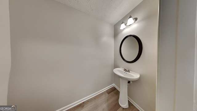 bathroom with hardwood / wood-style flooring, lofted ceiling, and a textured ceiling