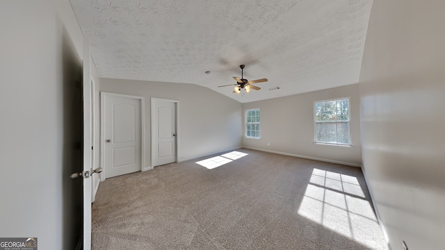 unfurnished room featuring a textured ceiling, ceiling fan, carpet flooring, and lofted ceiling