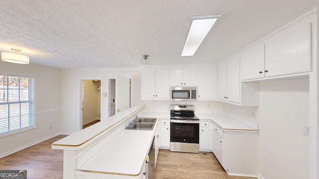 kitchen featuring sink, white cabinetry, a center island, light wood-type flooring, and appliances with stainless steel finishes