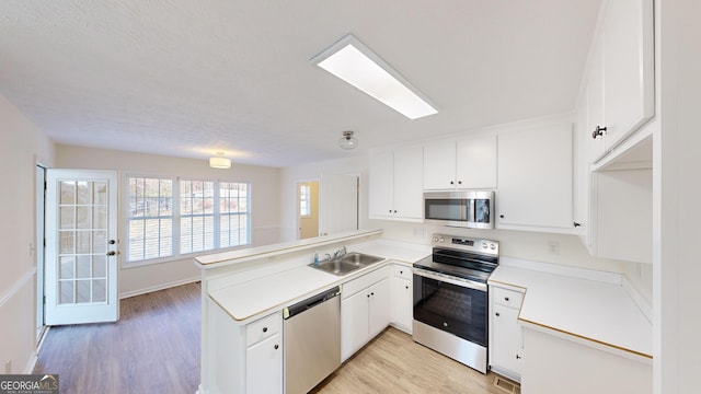 kitchen with white cabinetry, appliances with stainless steel finishes, kitchen peninsula, and sink