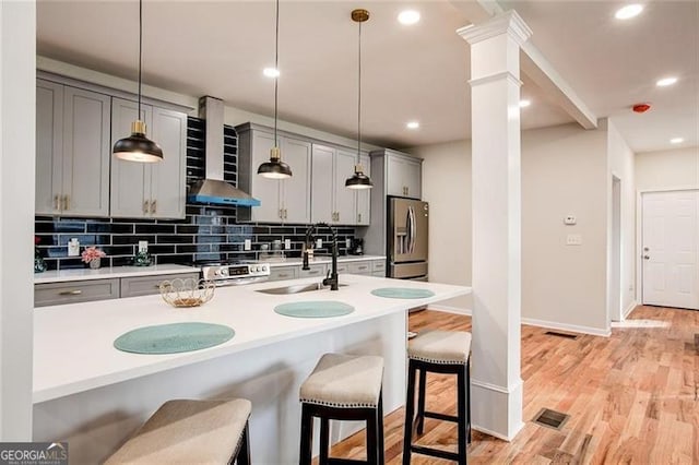 kitchen featuring stainless steel fridge with ice dispenser, decorative light fixtures, wall chimney exhaust hood, and sink