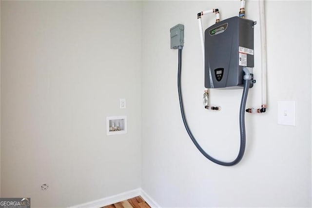 interior space with water heater, hookup for a washing machine, and hardwood / wood-style flooring