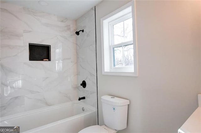 bathroom with tiled shower / bath combo, toilet, and a healthy amount of sunlight