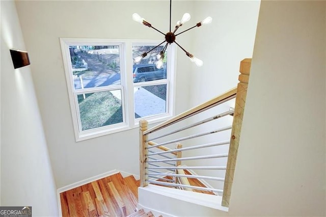 stairs with a chandelier and hardwood / wood-style floors