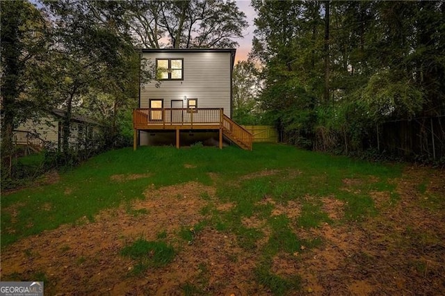 back house at dusk featuring a yard and a wooden deck