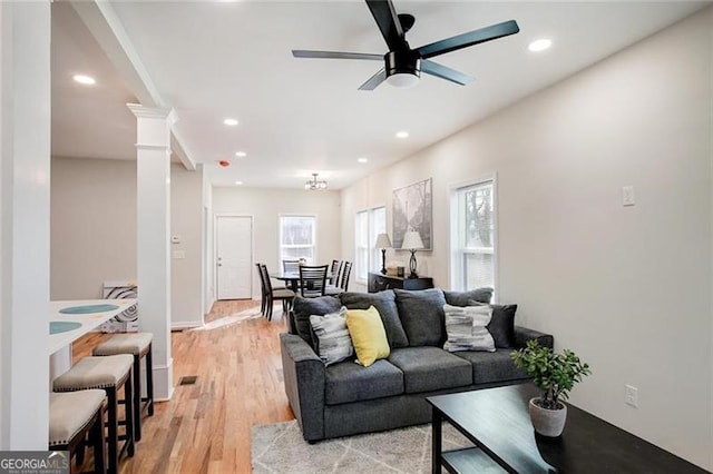 living room with ceiling fan, light wood-type flooring, and ornate columns