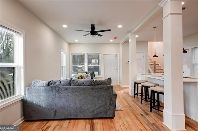 living room with ceiling fan, ornate columns, and light hardwood / wood-style flooring