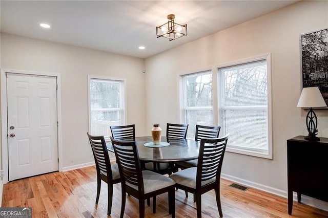 dining area featuring light hardwood / wood-style floors, a wealth of natural light, and an inviting chandelier