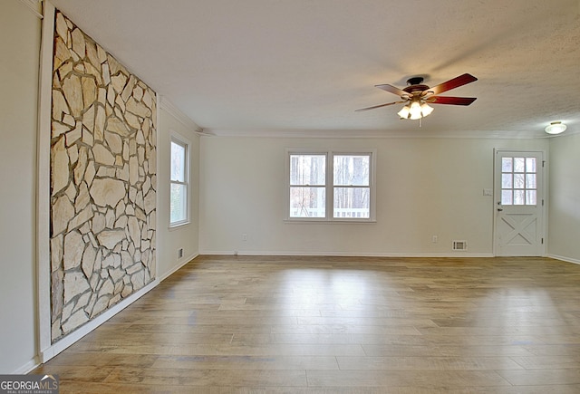 empty room with crown molding, a textured ceiling, ceiling fan, and light hardwood / wood-style floors