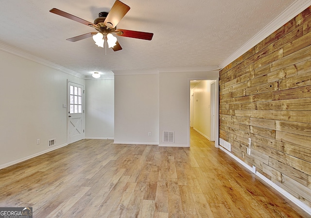 spare room with wood walls, crown molding, a textured ceiling, ceiling fan, and light hardwood / wood-style floors