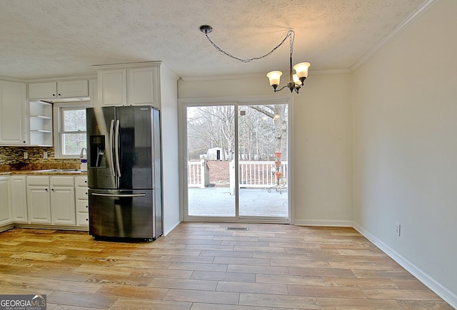 kitchen featuring stainless steel refrigerator with ice dispenser, white cabinetry, tasteful backsplash, and light hardwood / wood-style flooring