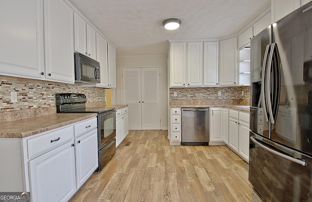 kitchen with white cabinetry, tasteful backsplash, black appliances, light hardwood / wood-style floors, and a textured ceiling